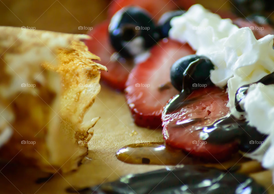 Strawberries, blueberries with whipped cream, syrup on French crepes closeup gourmet breakfast or brunch epicure photography 