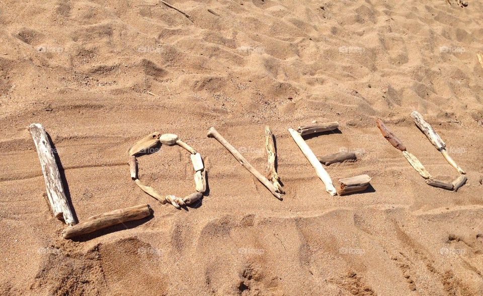 "Love you" written with driftwood on the beach