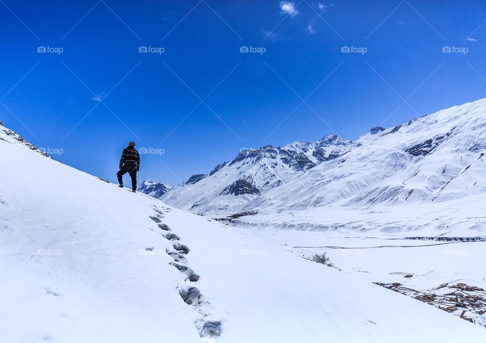 wanderlust trekker standing on top snow filled mountain leaving his footprints behind
