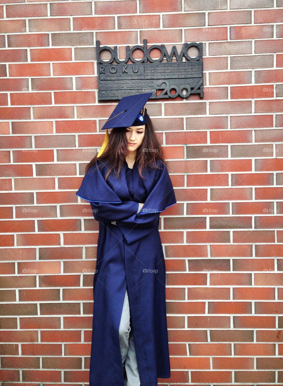 Graduate woman standing near the wall