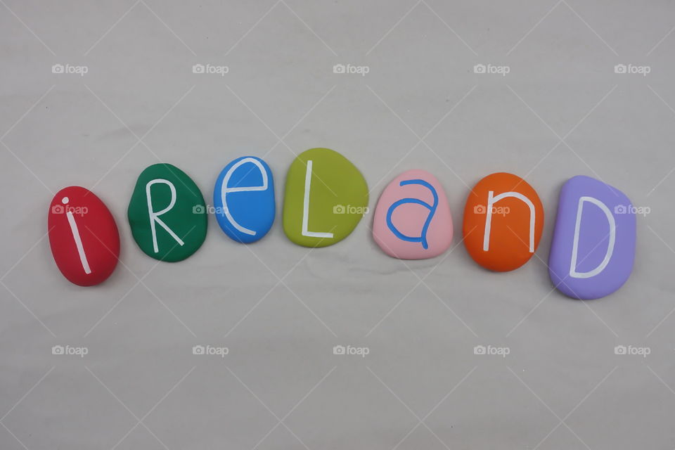 Ireland, country name with colored stones letters over white sand  
