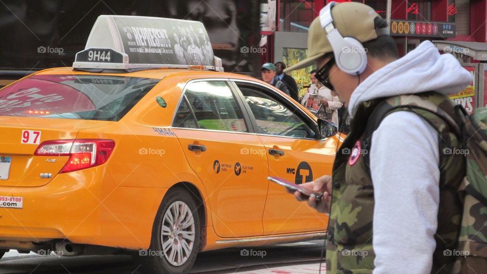City Taxi Cab and a Pedestrian with a Camouflage Vest, Headphones, and Sunglasses