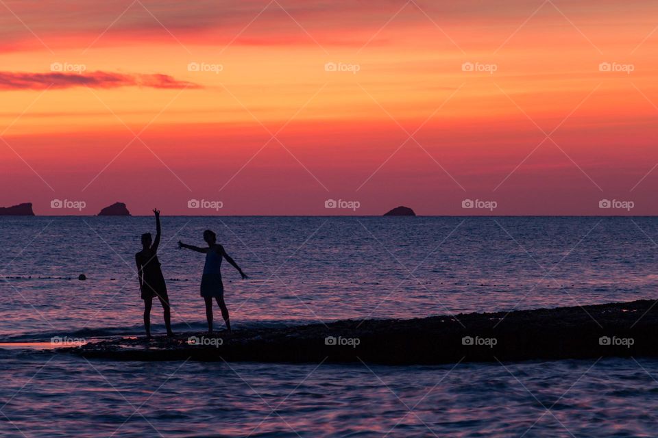 A couple dancing during the sunset in cala comte (Ibiza)