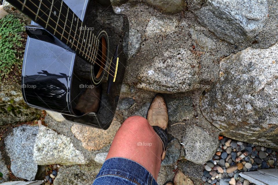 Country western musician woman sitting in cowboy boots with guitar point of view 