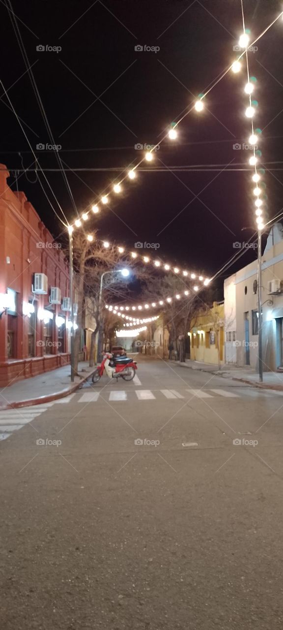 calle de un pueblo iluminado para darle alegría  a lugar y mucha luz varias cuadras