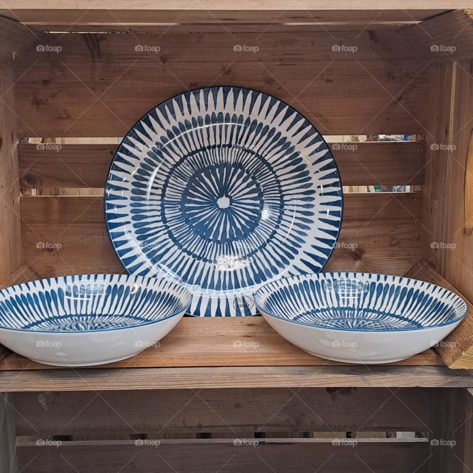 blue and white plate and dishes on display in wooden bix. shop