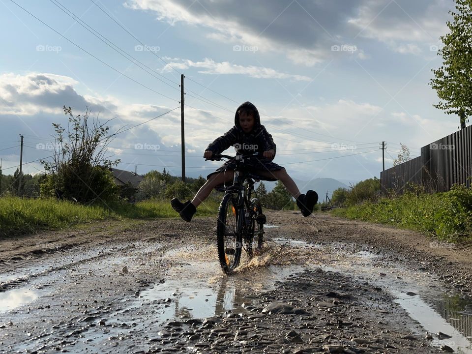 a child rides a bicycle through the puddles