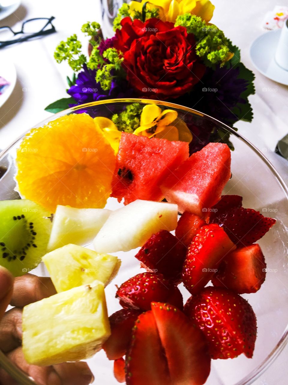 a small platter of fruit of all kinds like these can also become breakfast, on the table was a white towel, there was a small vase of flowers all kinds and colors