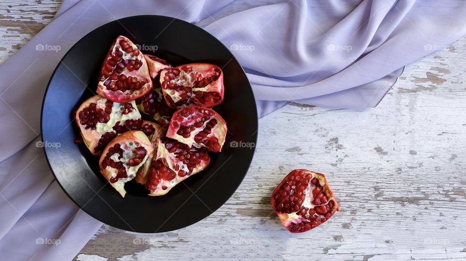 juicy and bright pomegranate on a black plate