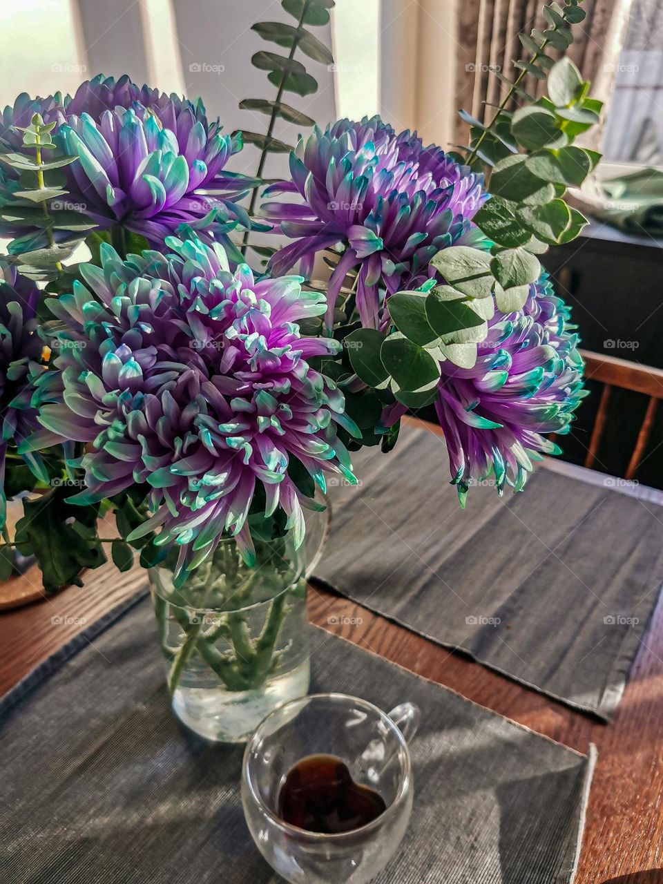 Gorgeous and beautiful vivid purple and blue flowers in a glass jar on a table with sunlights 