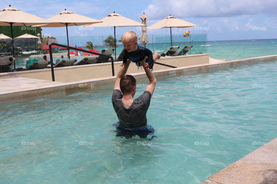 Dad and child having fun and playing on the pool 