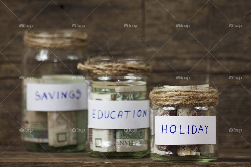 3 different jars; with money for holiday, education and savings