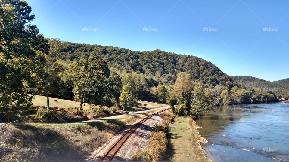 taking a picture of the beautiful mountains the blue sky and the railroad tracks below