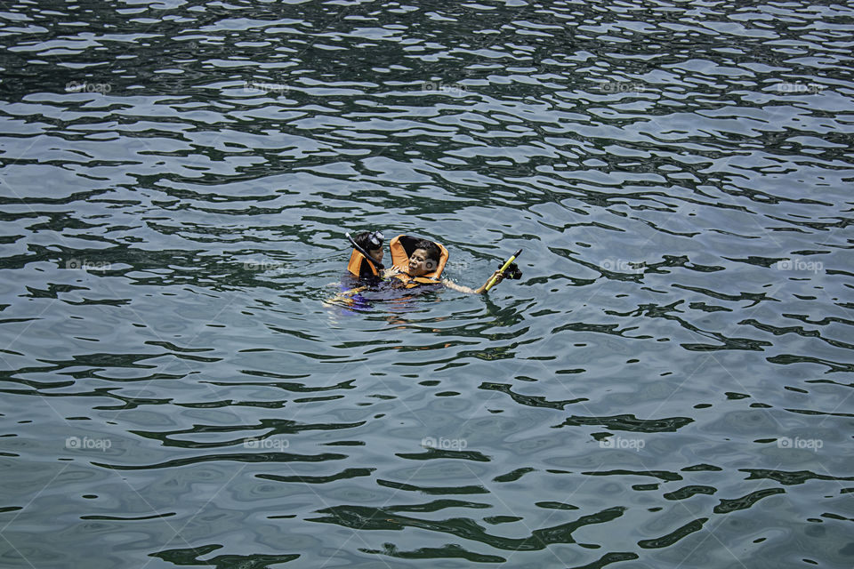 Mother and son wearing a life jacket, scuba diving in the sea.