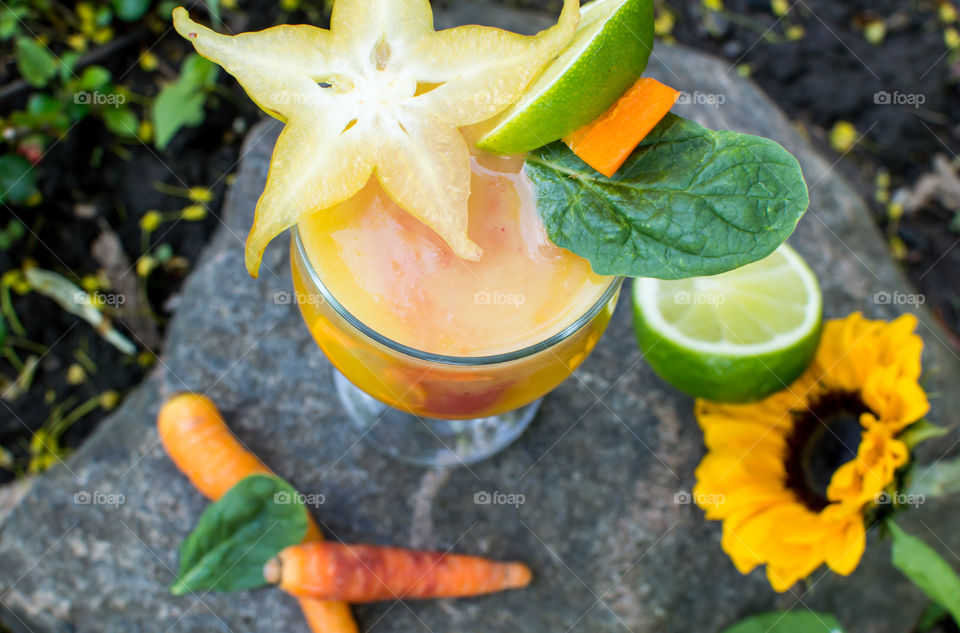 Fresh citrus and berry mixed tropical smoothie with elegant healthy organic ingredients garnish high angle view on stone rock sustainability and healthy lifestyle conceptual background 