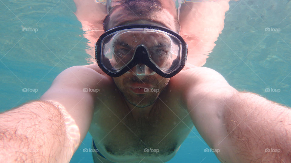 Man diving, man underwater smiling and relaxing in big blue sea with his camera