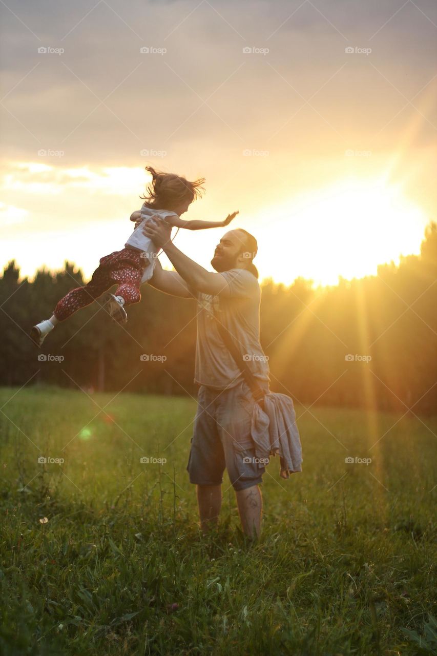Dad circling daughter in the rays of sunlight