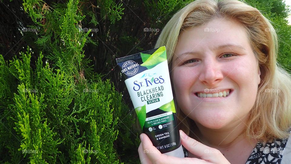 Young blonde woman holding product outdoors natural light