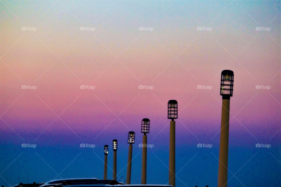 lampposts in descending order in backdrop of pink and blue hues of beautiful sunset
