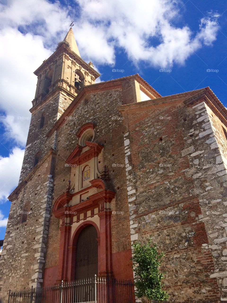 Looking up at old stone church in village of Alájar in Andalucia in Spain against a blue sky 