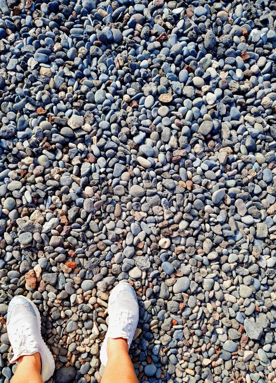 view from above on my sneakers , standing by the sea on pebbles