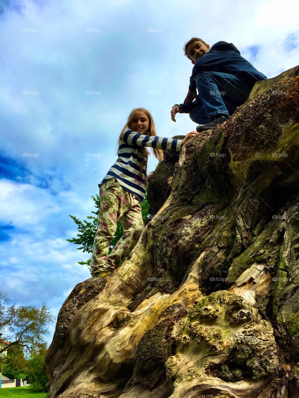 Low angle view of boy and girl on rock