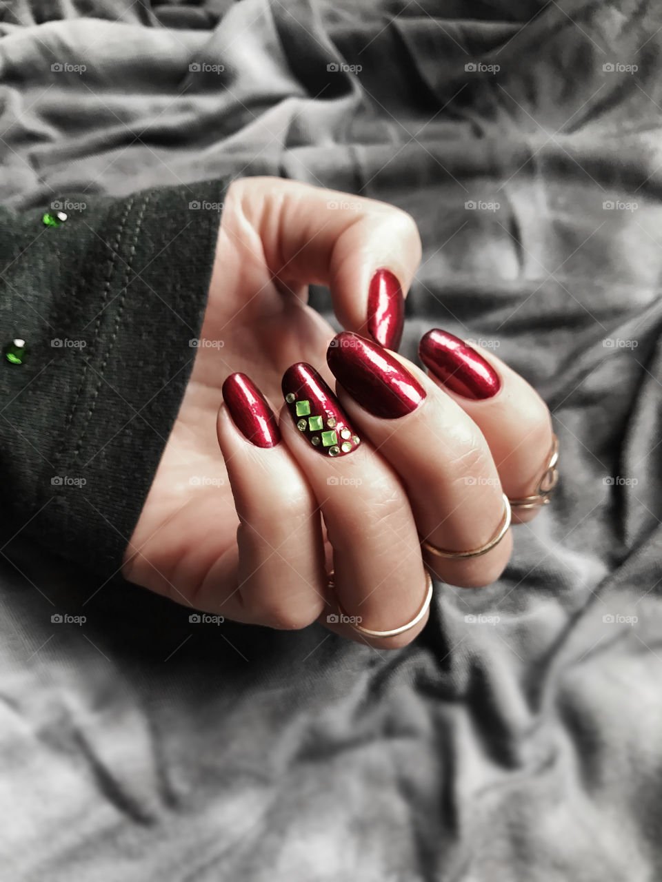 Red nail polish with green stones nail art 