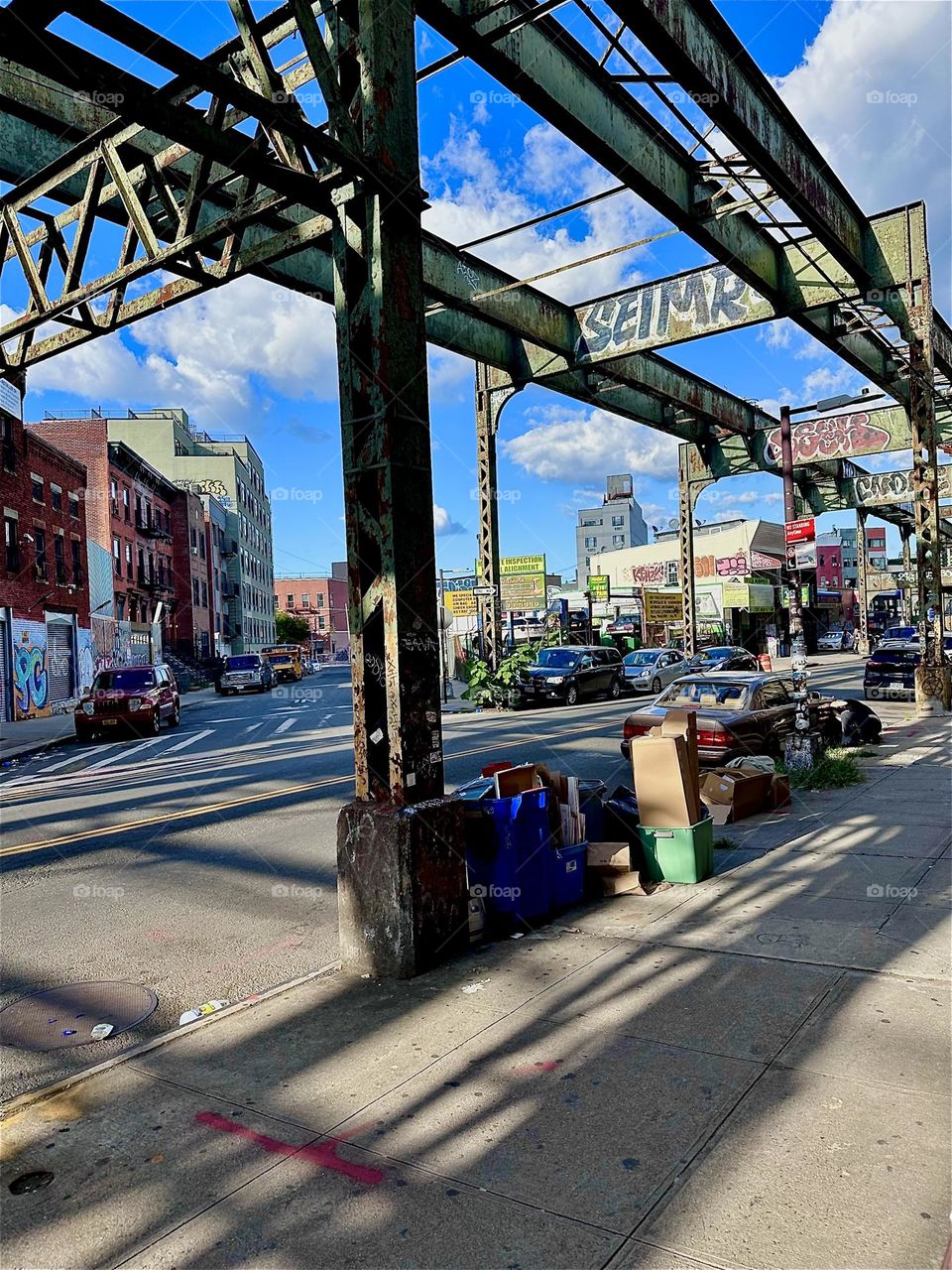 This is the multifaceted early industrial age overpass at “Myrtle Ave” in “Bushwick”, Brooklyn. Facing away from the “Broadway” intersection the afternoon sun casts intricate elongated shadows onto the asphalt. 2024. Hypnotic Productions