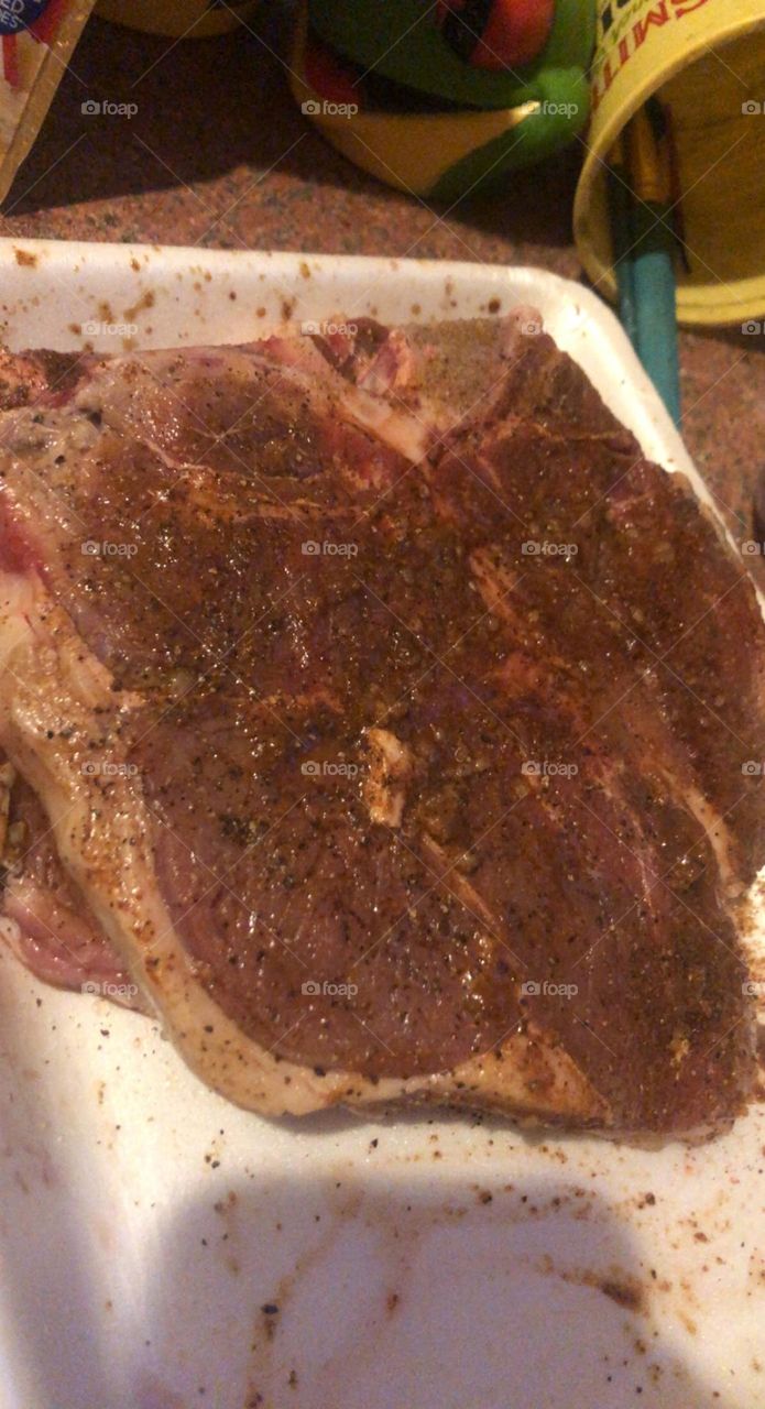 A steak seasoned and soaked in Worcestershire sauce getting ready to be cooked 