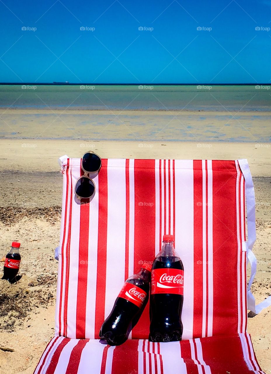 Playing up the reds in Coca Cola’s flagship colour, a “family” of various sizes of bottles of Coca Cola spending the day at the beach