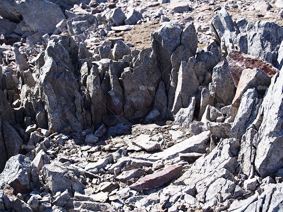 Jagged rocks and boulders along the shoreline of Ochoco Lake in Central Oregon on a sunny spring day.