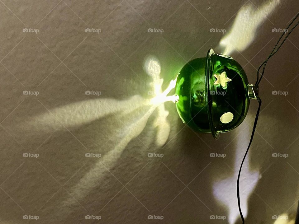 Green Christmas bell light making reflections on a wall