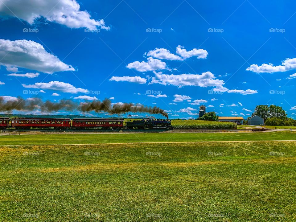 Train passing farm in summer day 