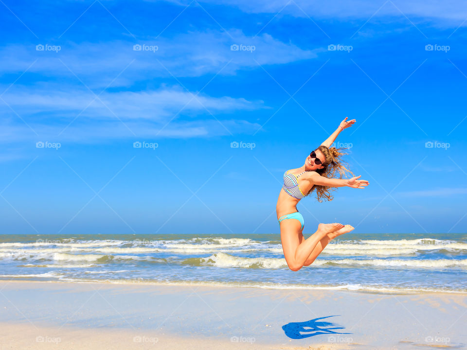 Woman jumping over sandy beach