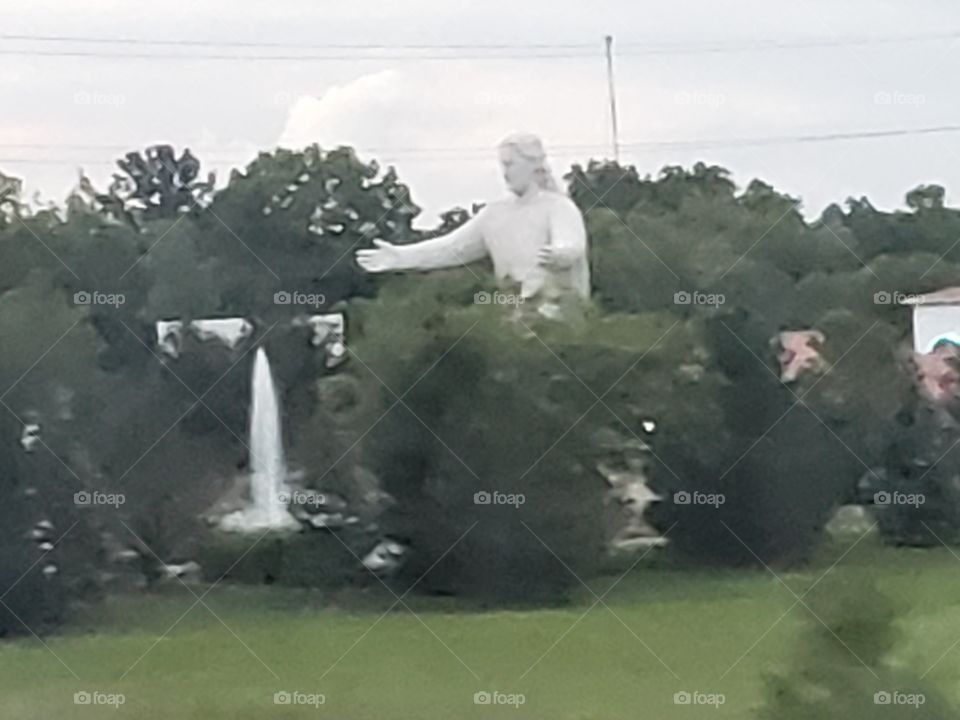 Huge statue surrounded by trees and water fountain