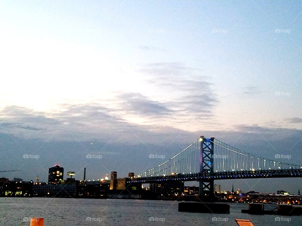 Bridge spanning river in Camden, NJ at  sunset