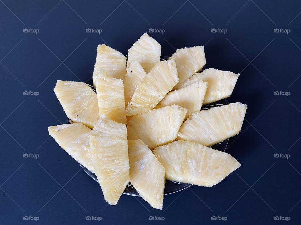 Peeled and sliced pineapple on a blue background 