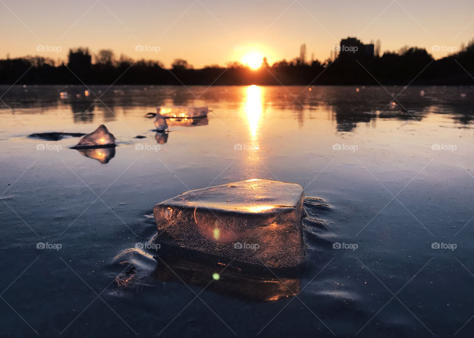 Pieces of ice on frozen lake water during the sunset 