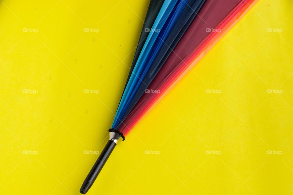 Multicolored umbrella on yellow background.