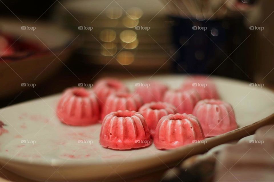 Small pink ice cream tarts stand on a white plate with lighting in the background