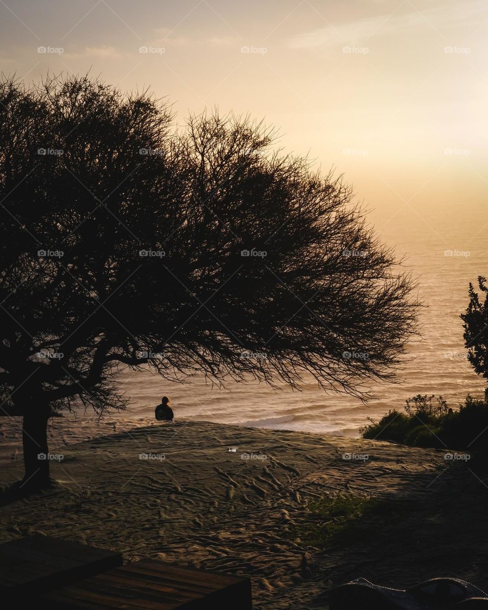 A person meditating near the ocean witnessing a very beautiful sunset at the golden hour!