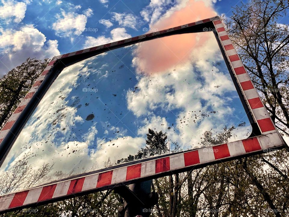 Reflection of a pink cloud in a traffic mirror at sunset