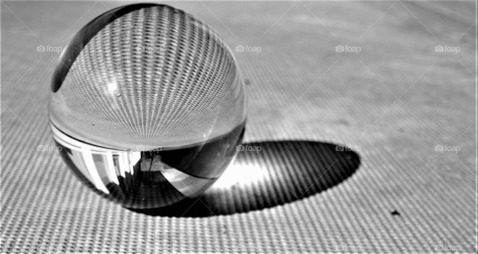 abstract black and white picture with crystal clear glass ball on a structured concrete surface