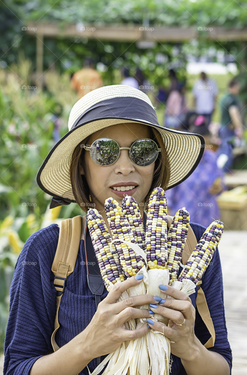 A woman holding the corn at the show in the farm.