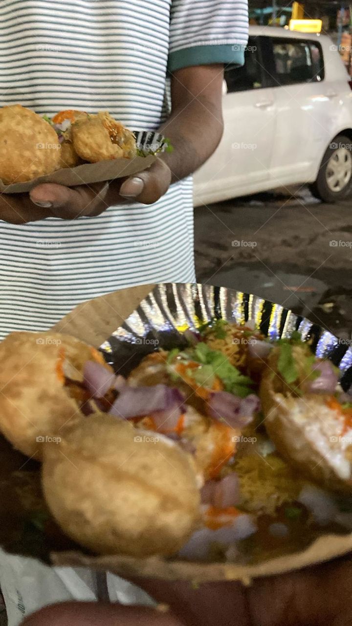 A tempting mouth watering dish on the road sided with lots of flavor, spice, sweetness  covered with curd and sev , coriander leaves and green chutney with fresh onion a totally full combo of colors.