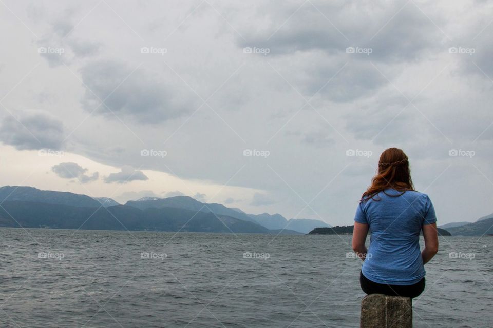 Woman sitting by a fjord