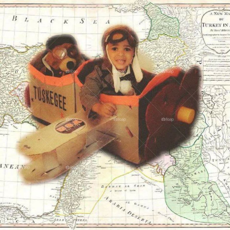 Toddler boy as Tuskegee Airman in box airplane with teddy bear 
co-pilot