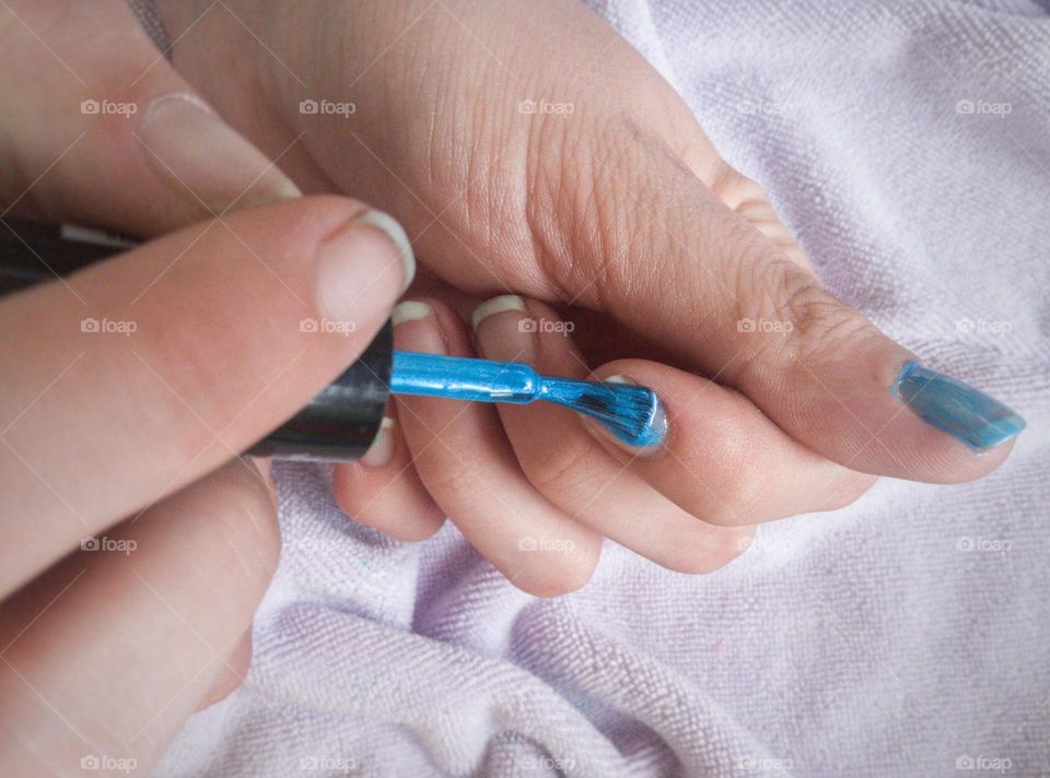 A bright blue nail polish being applied.