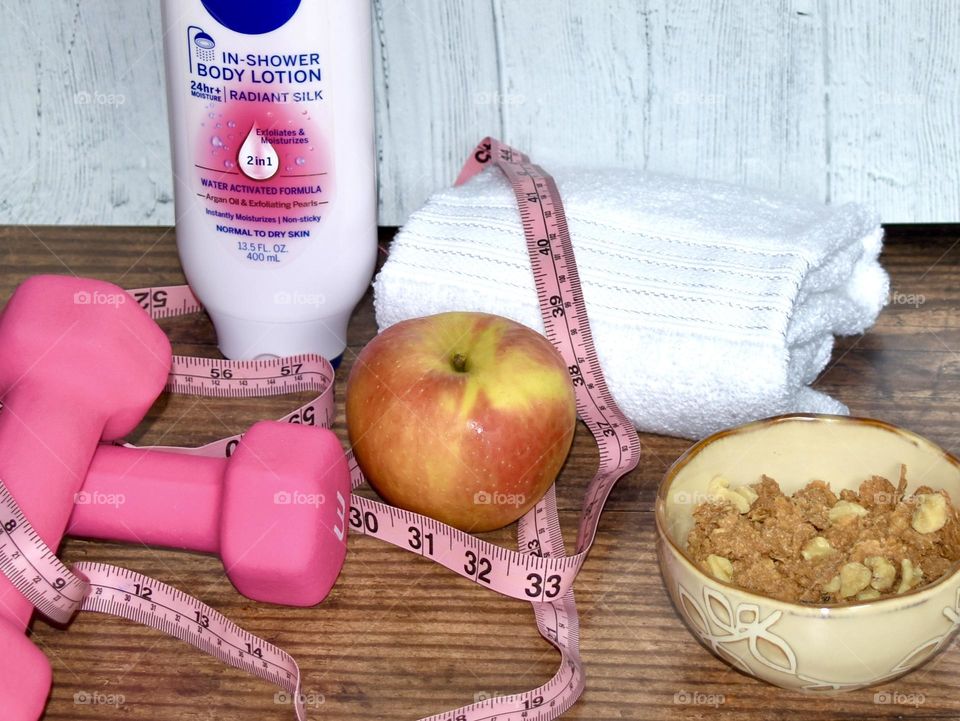 Healthy food, dumbbells, tape measure, and body lotion 