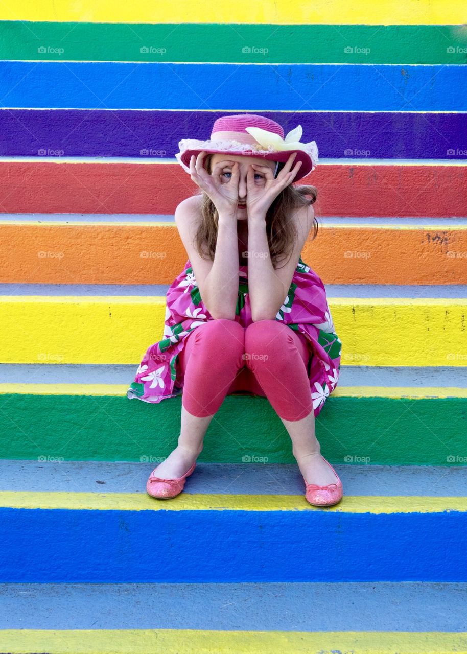 Girl makes funny face on bright rainbow stairs